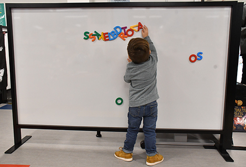 Child playing with magnetic letters on a whiteboard
