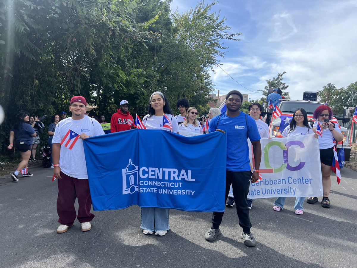 Central students hold a blue banner as they march in the Puerto RIcan Day parade.