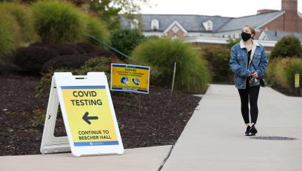 student walking past covid safety signs