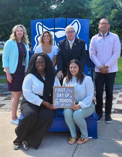 Group photo of members of the Office of the Dean holding sign displaying the first day of school text