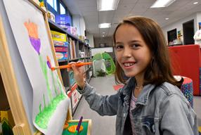 Young girls painting at an easel