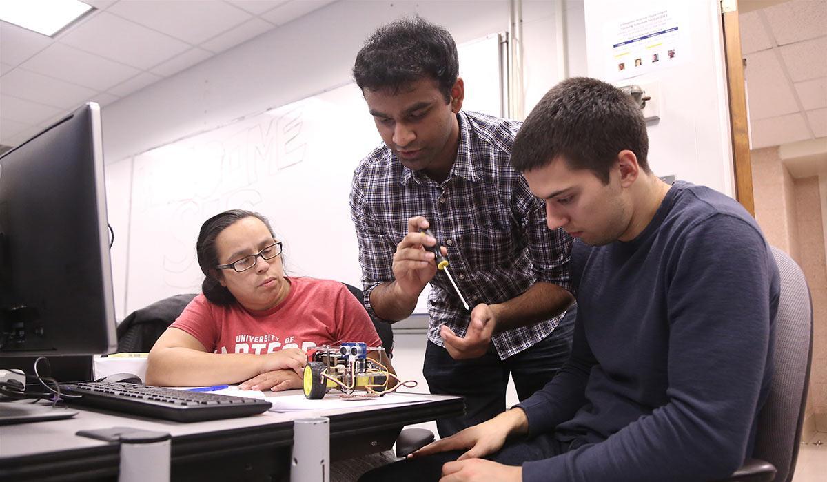 Students and professor at computer in lab