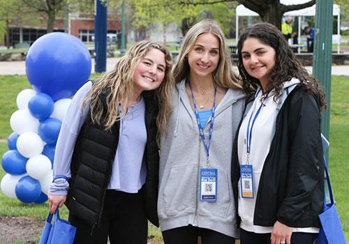 3 students outside wearing badges from Accepted Students Day