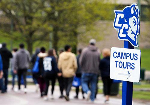 Campus Tours sign with crowd from campus tour in background