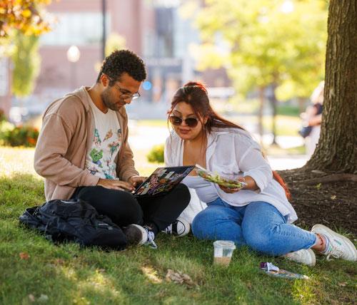 two students sitting under a tree