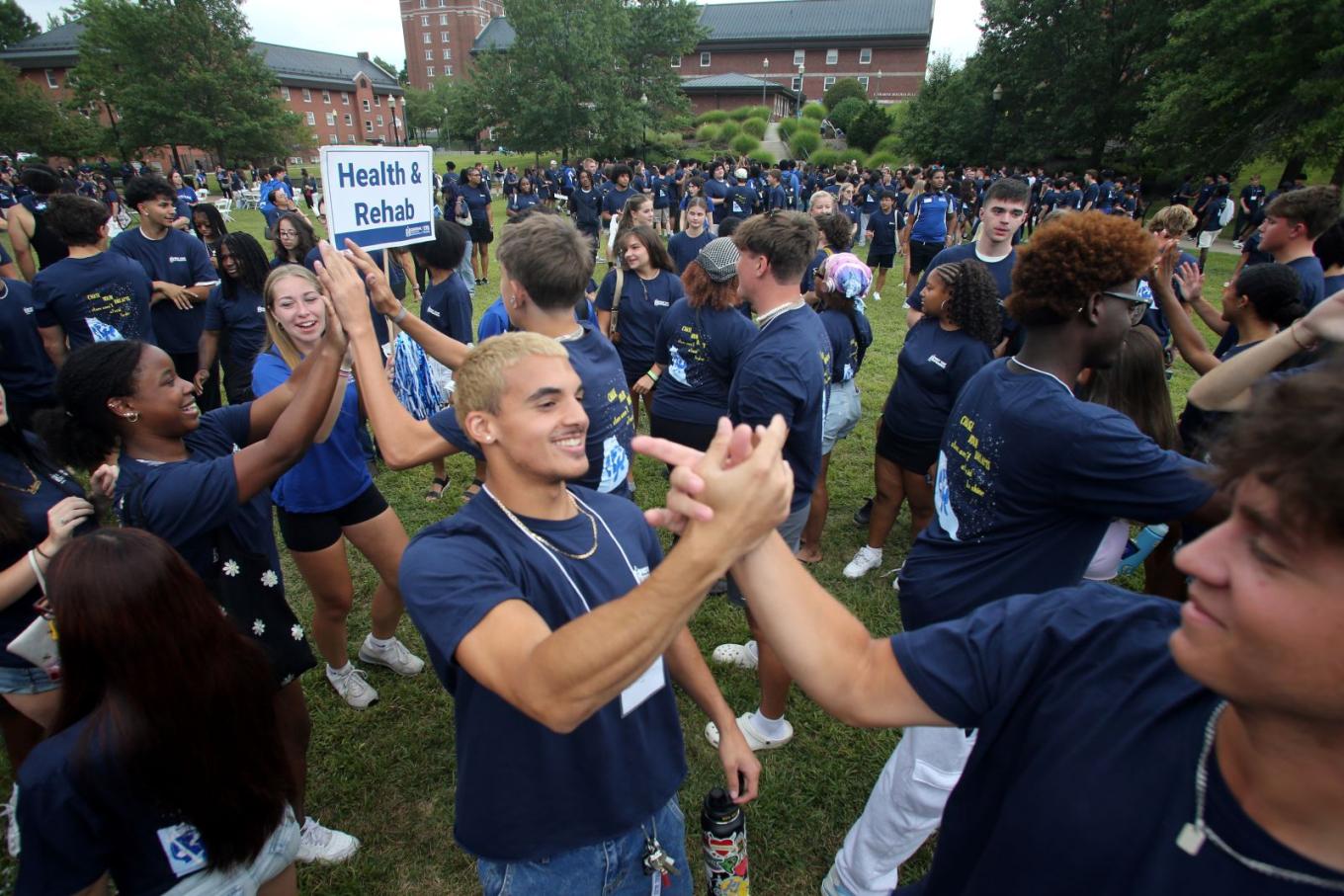 Students high-five each other after a successful class photo shoot on Vance lawn.