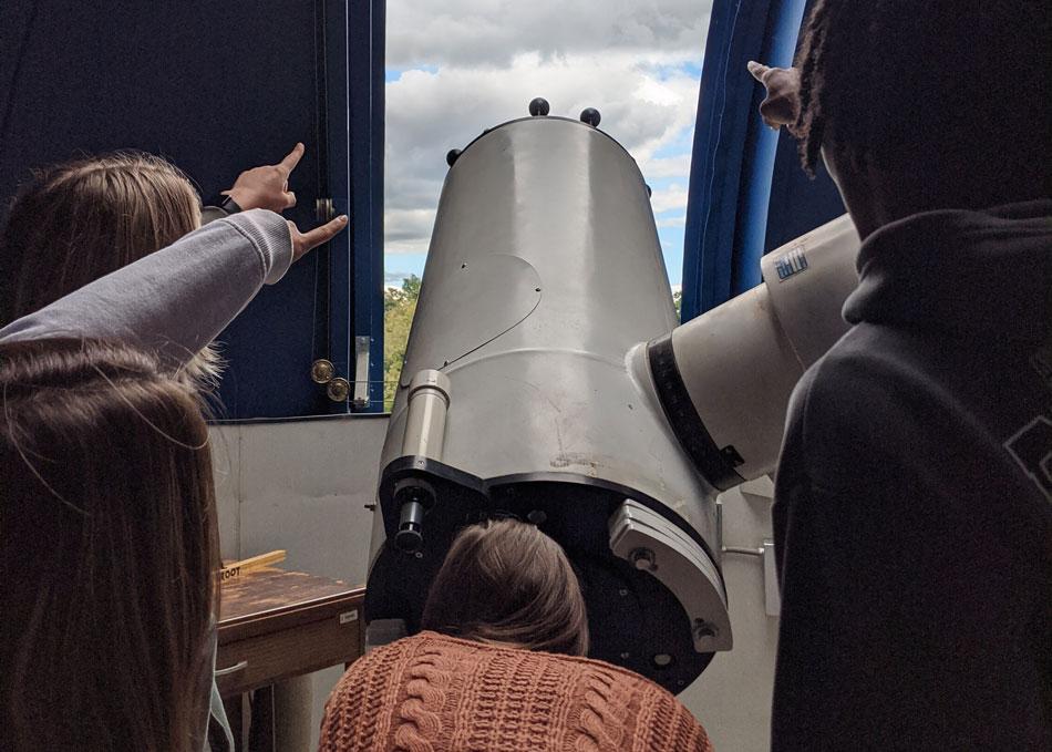 students looking through telescope in the observatory