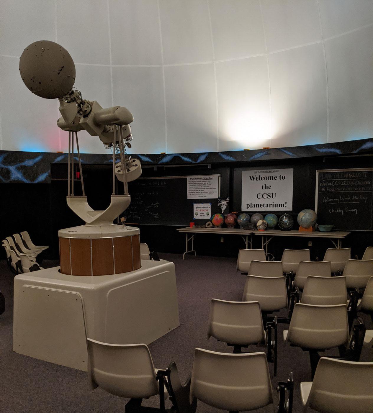 Planetarium projector with sign that says "Welcome to the CCSU Planetarium"