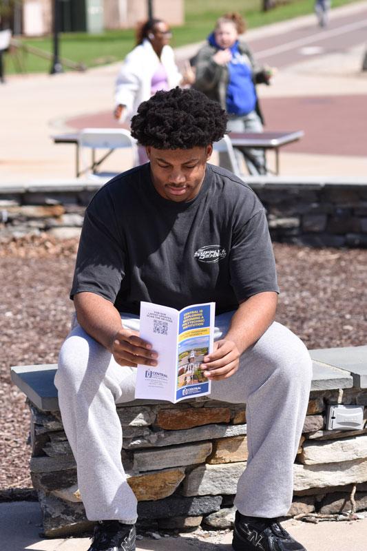 Student outside student center reading pamphlet