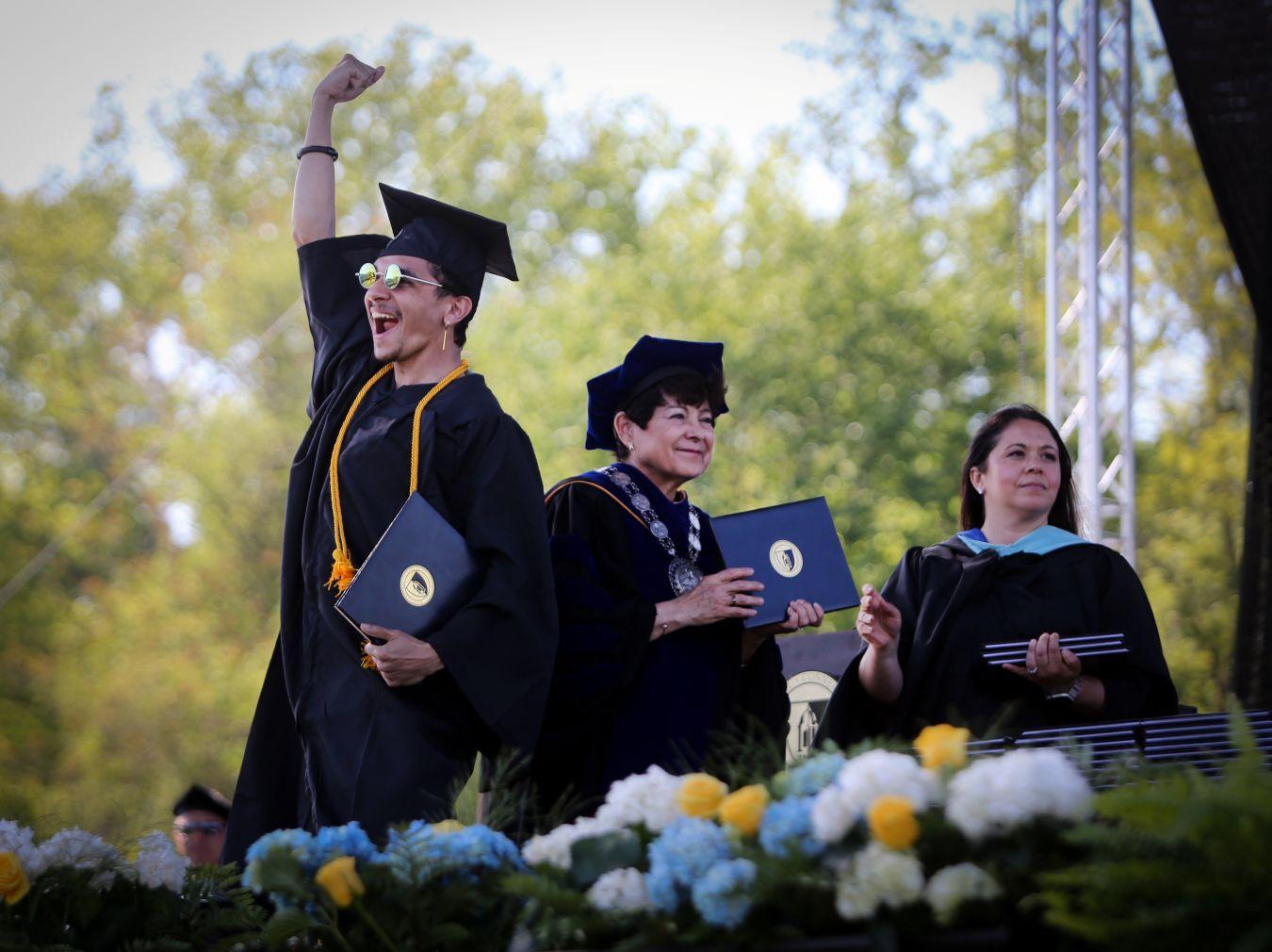 A student celebrates on the stage after receiving his diploma from President Toro