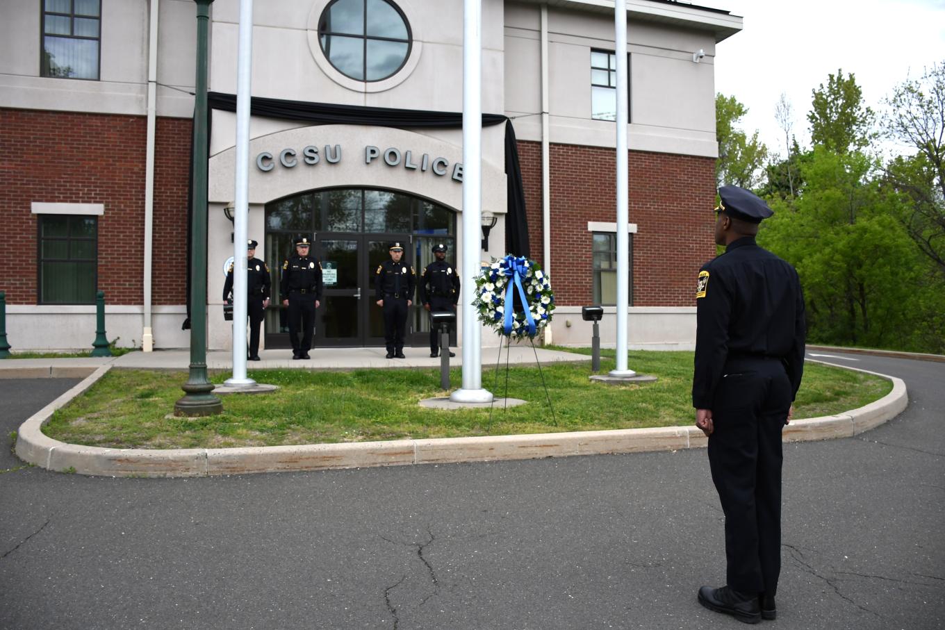 CCSU Police officers observe National Police Week on May 11. They are shown outside of the police department saluting a memorial wreath.