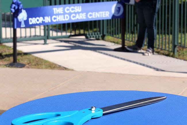 scissors in front of ribbon reading 'The CCSU Drop-In Child Care Center'