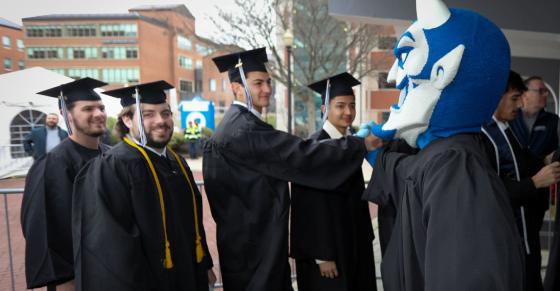 Central graduates high-five university mascot Kizer the Blue Devil.