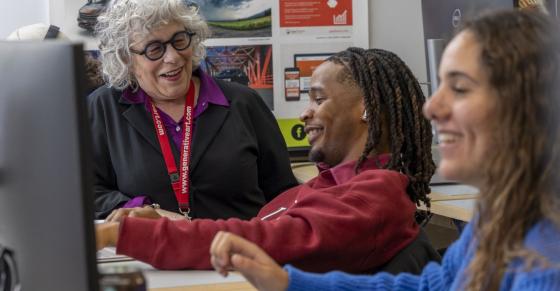 Students and a professor talk about a project in a graphic design classroom