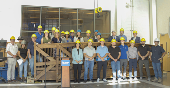 Central students, faculty, and staff pose next to a recently constructed timber bridge that will be installed on campus.