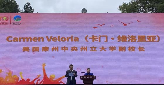 Dr. Carmen Veloria delivers remarks at the 40th anniversary celebration of the Ouyang Yu Experimental Middle School. Dr. Xudong Jia (left) translated her remarks into Chinese.