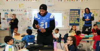 A Central football player speaks with Smalley Elementary School students