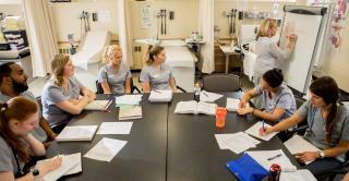 Nursing students sit around a table in class