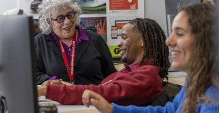 Students and a professor talk about a project in a graphic design classroom