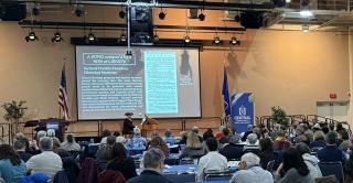 A historical musician performs at Alumni Hall in front of a full house. 