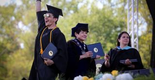 A student celebrates on the stage after receiving his diploma from President Toro