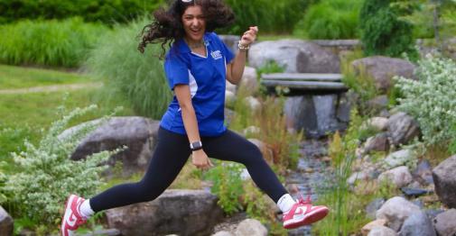 Student jumping over display pond