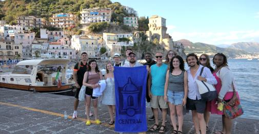 Central study abroad students on the Amalfi coast hold up a Central-logo banner.