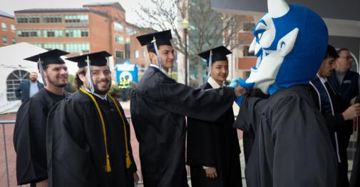 Central graduates high-five university mascot Kizer the Blue Devil.