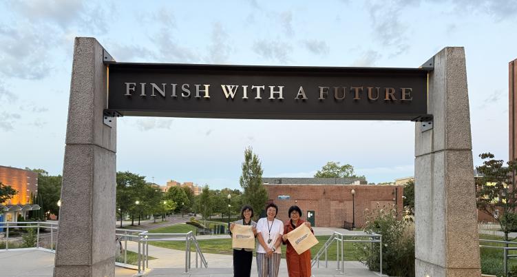 Members posing under Finish with a Future sign at Barnard Hall