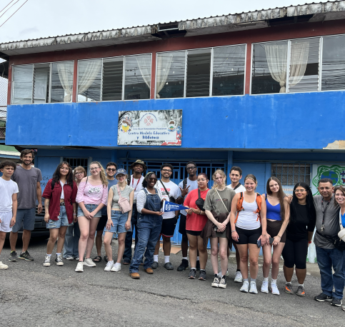 Students standing in front of a blue building 